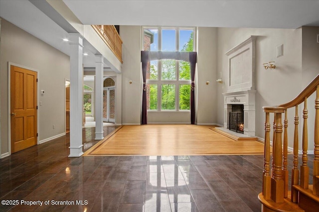 441 Hidden Lake Dr, East Stroudsburg, PA 18302 - entrance foyer featuring decorative columns, a lit fireplace, a high ceiling, and wood finished floors