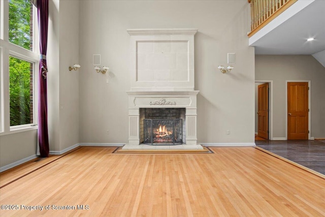 441 Hidden Lake Dr, East Stroudsburg, PA 18302 - unfurnished living room featuring wood finished floors, a warm lit fireplace, and a high ceiling