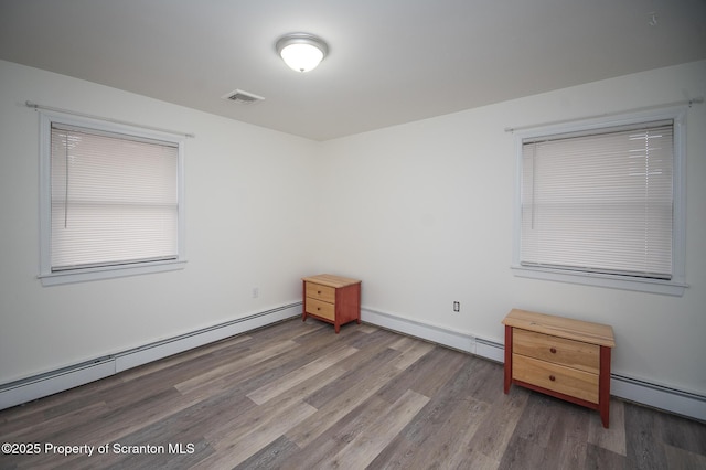 spare room with baseboard heating and wood-type flooring