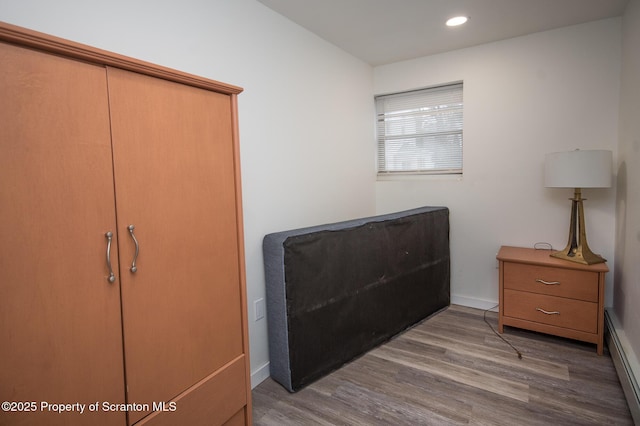 bedroom with hardwood / wood-style floors and baseboard heating