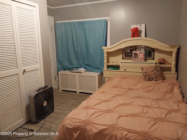 bedroom with crown molding, wood finished floors, and a closet