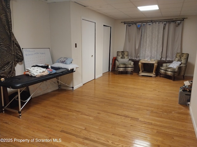 living area with a paneled ceiling, baseboards, and wood finished floors