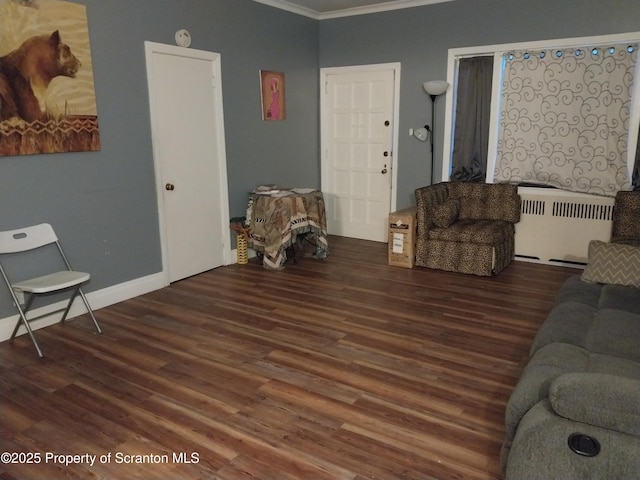 living area with radiator heating unit, wood finished floors, baseboards, and ornamental molding