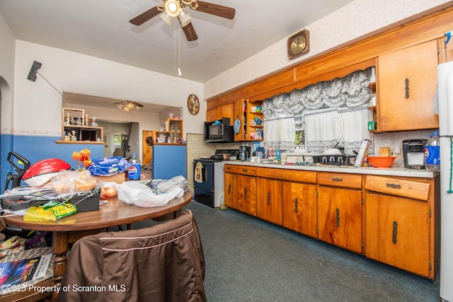1010 Wood St, Old Forge, PA 18518 - kitchen with black appliances, ceiling fan, dark carpet, light countertops, and brown cabinets