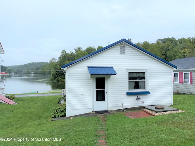 back of property featuring a lawn and a water view