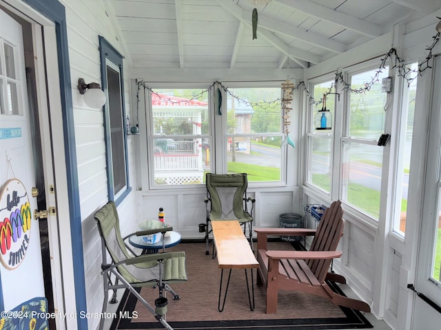 sunroom / solarium with lofted ceiling with beams, a healthy amount of sunlight, and wood ceiling