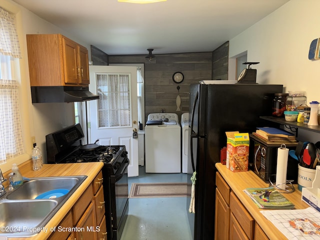 kitchen with concrete flooring, sink, black appliances, independent washer and dryer, and plenty of natural light