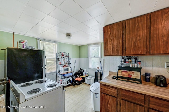 126-128 S Rebecca Ave S, Scranton, PA 18504 - kitchen with white range with electric stovetop, light countertops, decorative backsplash, light floors, and freestanding refrigerator