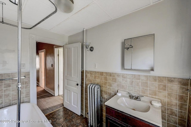 126-128 S Rebecca Ave S, Scranton, PA 18504 - full bath with radiator, tile walls, vanity, a tub to relax in, and wainscoting