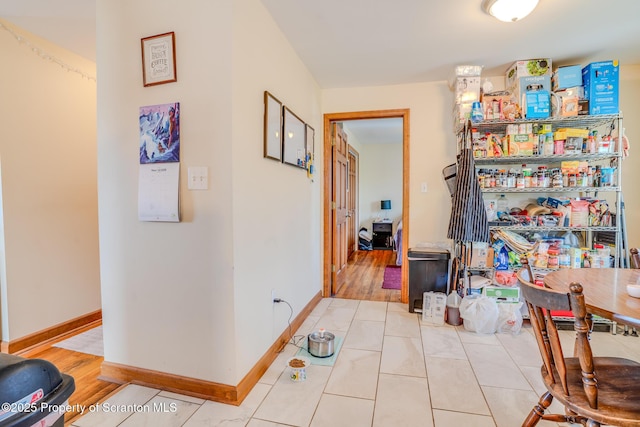 corridor featuring light tile patterned floors and baseboards