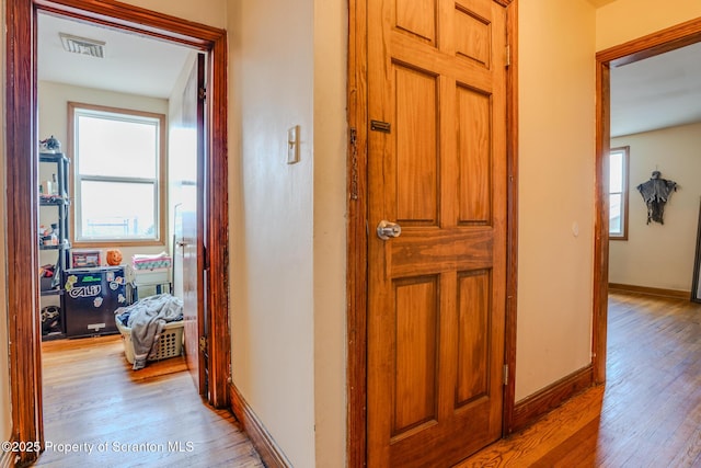hallway featuring baseboards, visible vents, and light wood-style flooring
