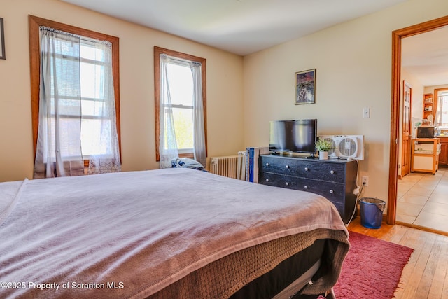 bedroom featuring radiator heating unit and hardwood / wood-style flooring