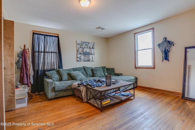 living room with baseboards, visible vents, and light wood-style flooring