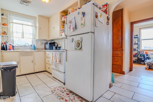 kitchen with visible vents, freestanding refrigerator, open shelves, light tile patterned floors, and range