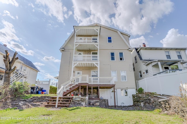 back of property featuring fence, a lawn, stairway, and a gambrel roof