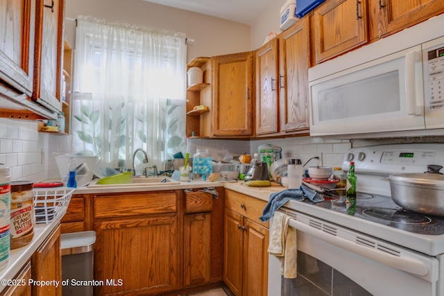 kitchen with a sink, white appliances, light countertops, brown cabinetry, and tasteful backsplash