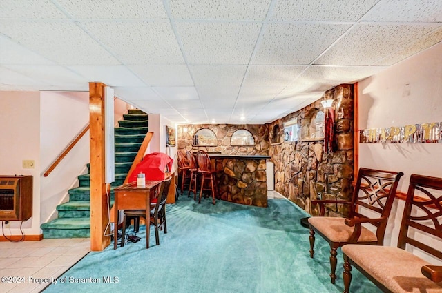 interior space with heating unit, a paneled ceiling, and carpet