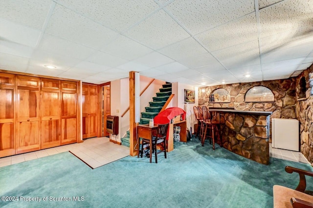 interior space featuring a drop ceiling, light carpet, and heating unit