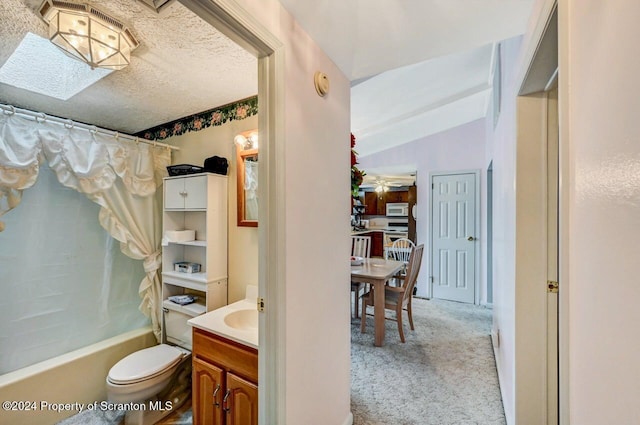 full bathroom featuring vaulted ceiling with skylight, a textured ceiling, vanity, shower / bath combo with shower curtain, and toilet