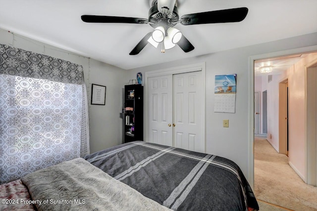 bedroom with a closet, ceiling fan, and light colored carpet