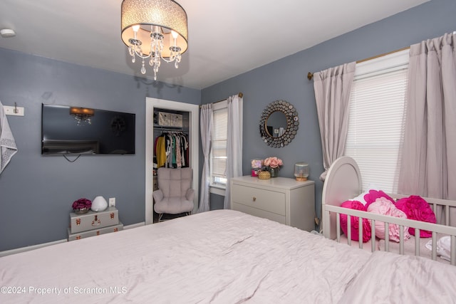 bedroom with multiple windows, a closet, and a notable chandelier