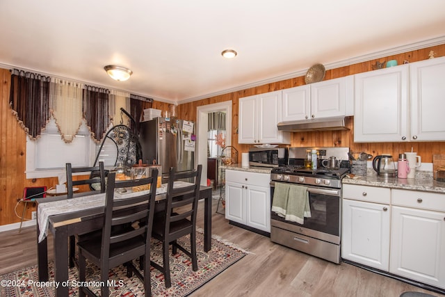 kitchen with white cabinets, light stone countertops, stainless steel appliances, and light hardwood / wood-style flooring