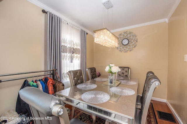 dining room with a chandelier, hardwood / wood-style floors, and crown molding