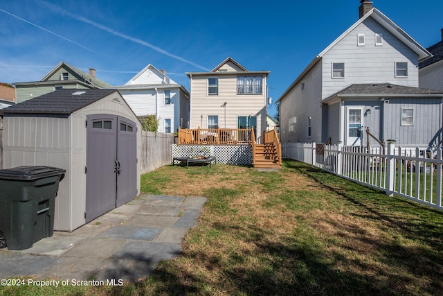 rear view of property featuring a shed, a deck, and a yard