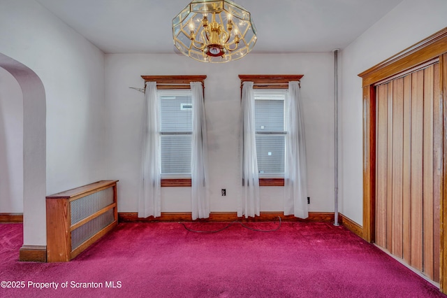 empty room featuring a notable chandelier and carpet flooring