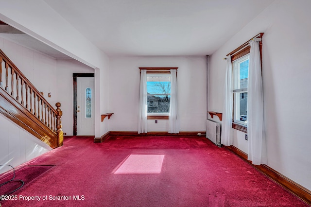 unfurnished room with radiator heating unit, carpet floors, and a wealth of natural light