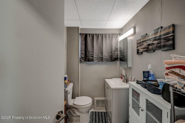 bathroom with visible vents, a drop ceiling, vanity, and toilet