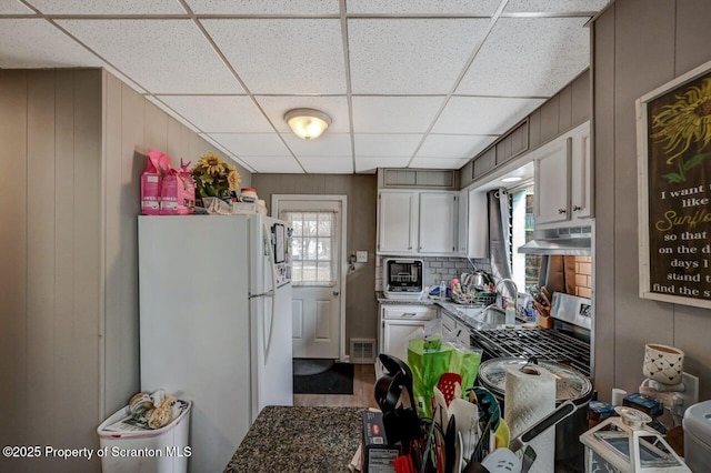 kitchen featuring a paneled ceiling, visible vents, freestanding refrigerator, gas range, and under cabinet range hood