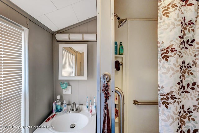 full bathroom with vaulted ceiling, curtained shower, and a sink