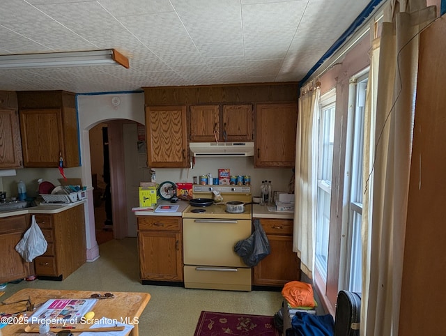 430 14th Ave, Scranton, PA 18504 - kitchen with white electric stove, under cabinet range hood, brown cabinets, arched walkways, and light countertops