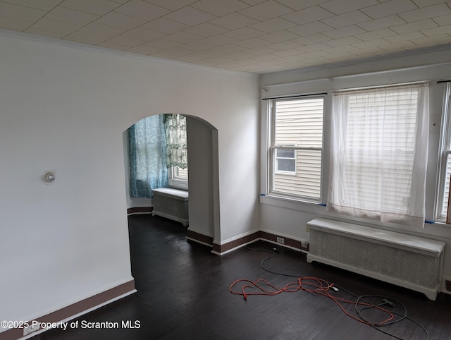 430 14th Ave, Scranton, PA 18504 - empty room with radiator, arched walkways, ornamental molding, wood finished floors, and baseboards