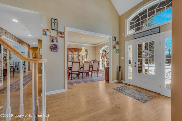 entrance foyer with high vaulted ceiling and light hardwood / wood-style floors