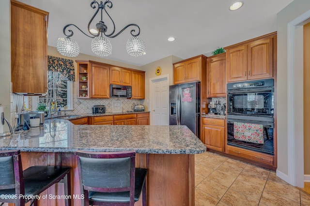 kitchen with dark stone countertops, decorative light fixtures, kitchen peninsula, and black appliances