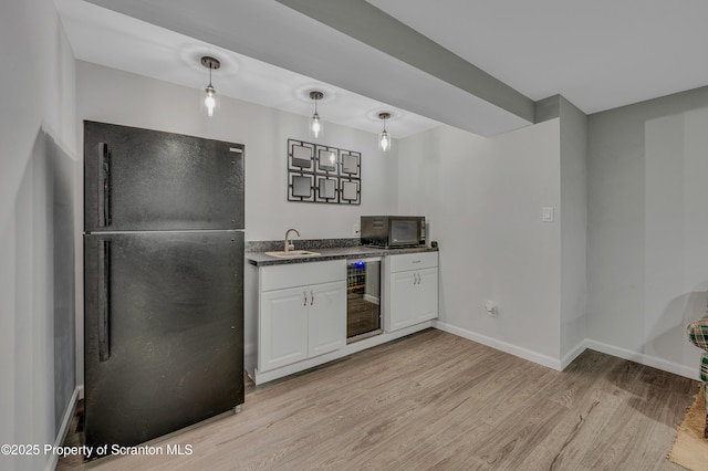 kitchen with sink, white cabinetry, light wood-type flooring, beverage cooler, and black appliances