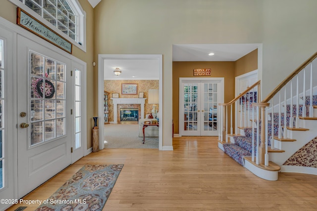 foyer entrance featuring a towering ceiling, french doors, and light wood-type flooring