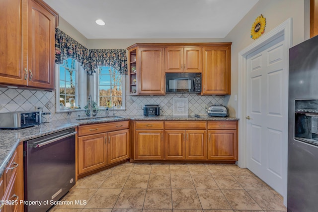 kitchen with light stone counters, sink, tasteful backsplash, and black appliances