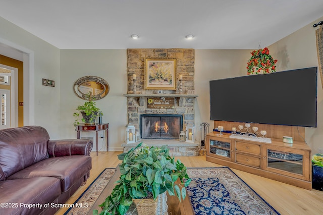 living room featuring a stone fireplace and light wood-type flooring