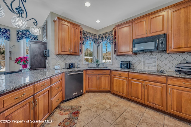 kitchen featuring sink, hanging light fixtures, black appliances, stone countertops, and decorative backsplash