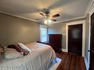 bedroom featuring ceiling fan, ornamental molding, and dark wood-type flooring