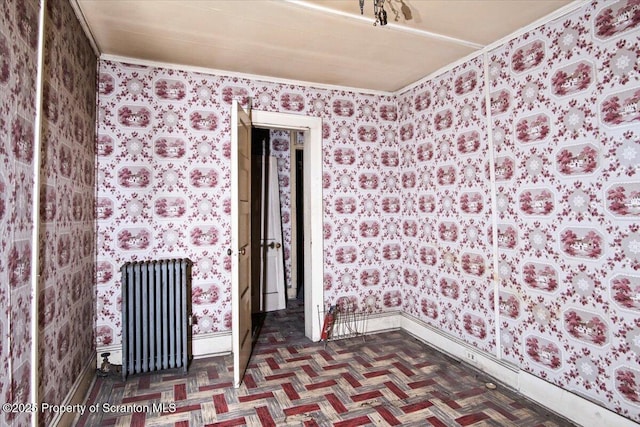 spare room featuring radiator and parquet floors