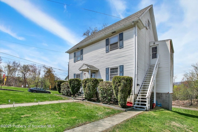 view of front of home featuring stairway and a front lawn