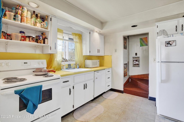 kitchen featuring white appliances, light countertops, white cabinets, and a sink
