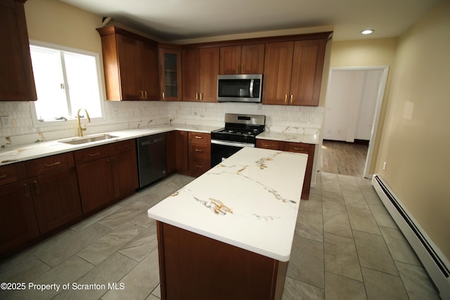 kitchen featuring a baseboard heating unit, stainless steel appliances, light stone countertops, a kitchen island, and sink