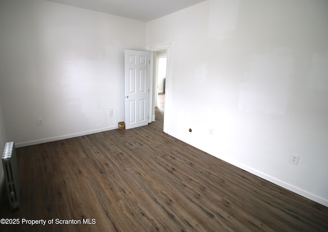 empty room featuring radiator and dark hardwood / wood-style floors