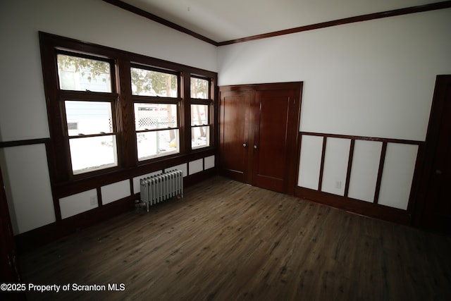 unfurnished room with radiator, dark wood-type flooring, and ornamental molding