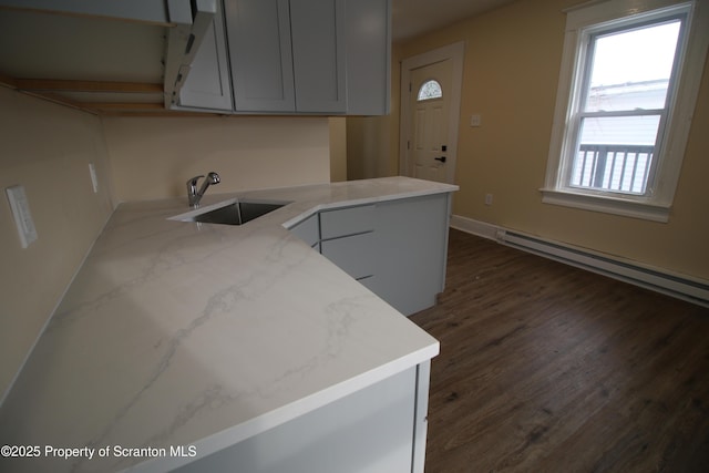 kitchen featuring a baseboard heating unit, dark hardwood / wood-style flooring, sink, kitchen peninsula, and light stone counters